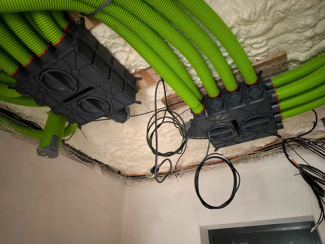 Zelené flexibilné vzduchovody rekuperácie napojené na dva rozdeľovacie boxy pod zatepleným stropom